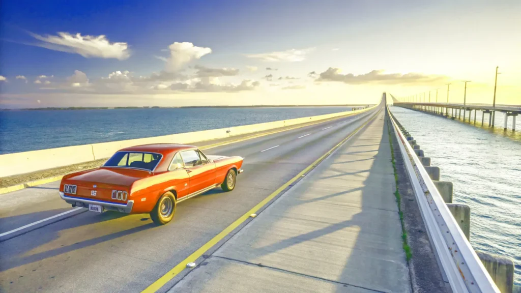 A classic red convertible driving over the scenic Overseas Highway in Florida at sunset during an epic east coast road trip.
